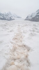 Footprints in Snow Leading Towards Glacial Mountains Under Grey Sky