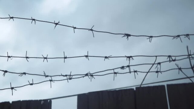 Barbed wire against a cloudy sky, close-up.