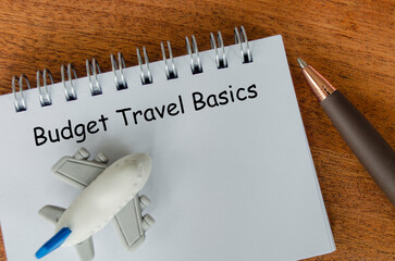 Flat lay of Budget Travel Basics notepad and toy airplane. Travel budgeting with conservation in...