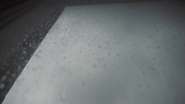 Raindrops flow down the window glass.