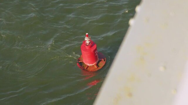 Red buoy in riever water as safety warning and navigation marker at harbor or port