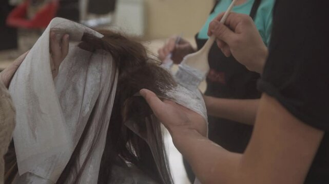 Several hair specialists coloring a client's hair in a beauty salon.