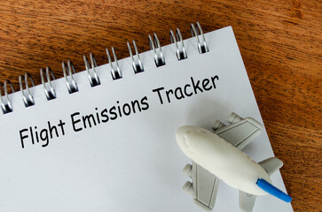 Flight Emissions tracker text on white notepad with small airplane background. Environmental...