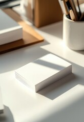 A close-up of two sleek business cards with customizable details, placed on a white desk, with natural light highlighting their features