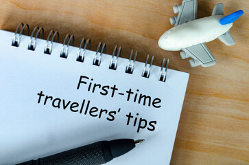 Top view of First Time Traveller tips text on white notepad. Getaway concept.