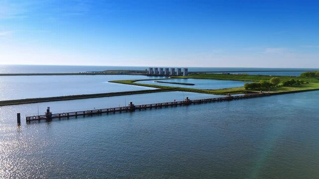 Flying closer to the dikes on the lake in Lelystad, the Netherlands. Approaching the dam with sluices. Aerial view.