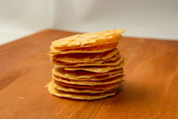 Almond crispy cookies with grated cheese, thin texture, isolated on white background, piled on a wooden cutting board