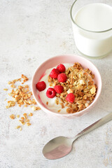 vertical photo with Yogurt with granola, raspberries and a glass of milk for breakfast