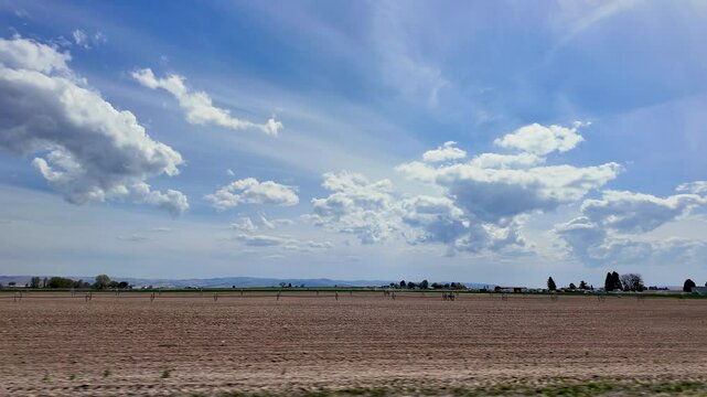 A view of the landscape and farmland in Twin Falls, Idaho driving on Kimberly Road in slow motion.