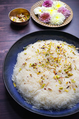 Closeup of Sutarfeni, a traditional Indian sweet made from fine sev soaked in sweet saffron flavored milk, garnished with dry fruits. Perfect for festive celebrations and Indian cuisine themes. copy