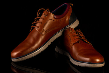 Men's leather brown shoes on a black background.