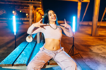 Young woman urban dancer performing at night with led lights