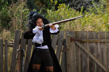 Beautiful female musketeer with an old gun in her hands