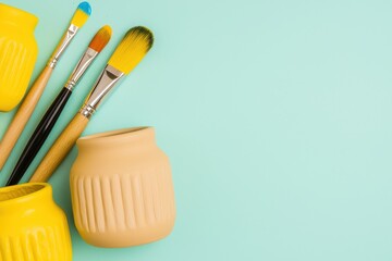 Colorful paintbrushes and ceramic jars arranged artistically on a pastel background.