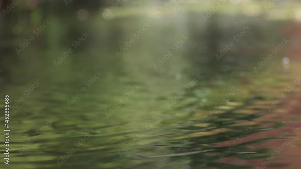 Poster gentle raindrops creating expanding circular ripples across calm water surface, reflecting surroundi