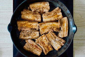 Fried Pork Belly in Cast Iron Pan — Slices of seasoned pork belly cooked in a cast iron skillet, golden brown and ready to serve. Close-up of traditional meat dish preparation.