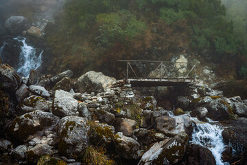 Beautiful Himalayan Glacial Waterfalls in the Mountains with a Bridge in the Langtang Region of...