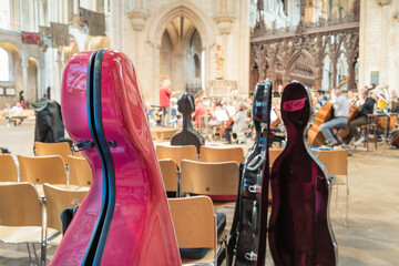Shallow focus of large hello string instrument cases seen in a famous English cathedral during a live performance. The orchestra can be seen in the background. © Nick Beer