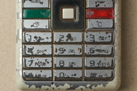 close-up of worn out physical keypad of old obsolete mobile phone, mechanical buttons arranged in grid of T9 format or layout with navigation keys and call buttons