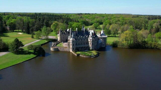 France Missillac Chateau de la Bretesche aerial 4K. Medieval castle on lake in Briere Regional Park. Luxury hotel and golf resort scenery. Historic French landmark cinematic drone travel video