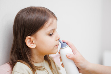 child is sick in bed. Mom gives medicine to her daughter. Mom drips her daughter's nose. Concept...