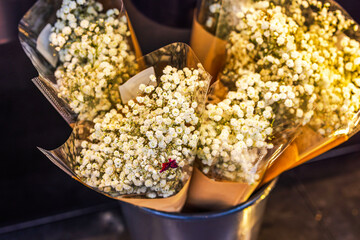 Bouquets of fresh white baby's breath flowers wrapped in paper and plastic in metal flower bucket...