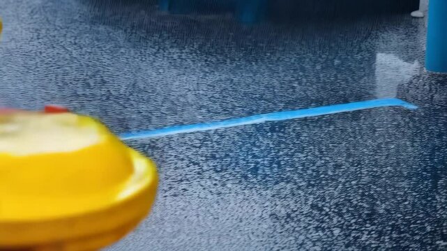 Several brightly colored fire hydrants sit in a row on wet pavement with water droplets.