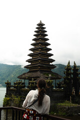 Chica de espaldas mirando templo budista en un lago, Bali indonesia