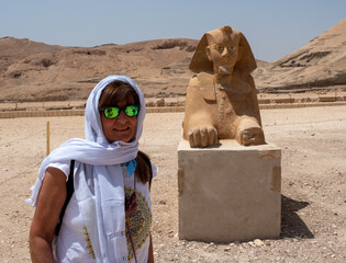 Tourist woman posing with an Egyptian Sphinx in the desert in Luxor, Egypt.