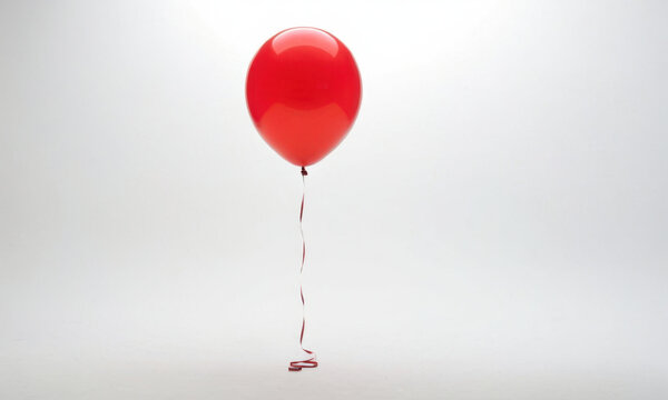 A red balloon floating in the air with a string attached, suitable for use in illustrations about childhood, adventure or whimsy