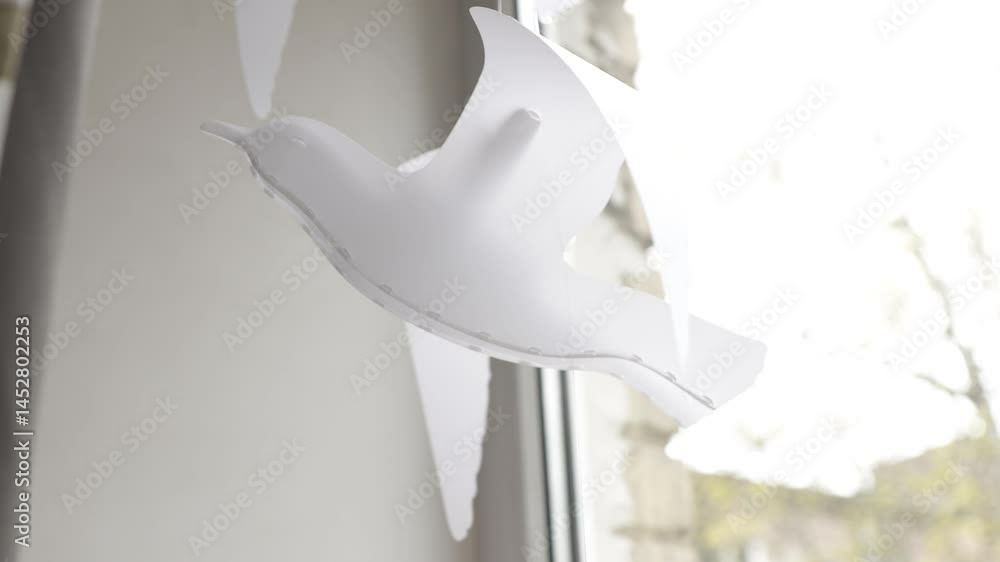 Poster a close-up shot of a paper bird hanging from a window, great for spring or easter-themed designs
