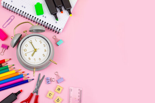 A collection of Colorful Stationery and Clocks displayed beautifully on a Pink Background