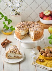 Round shortcrust pastry pie with apples, walnuts and sour cream soufflé on a cake stand against a light concrete background. Recipes apples.