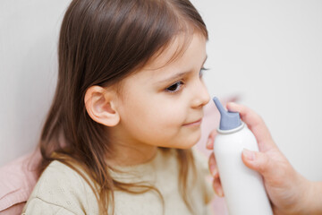 child is sick in bed. Mom gives medicine to her daughter. Mom drips her daughter's nose. Concept...
