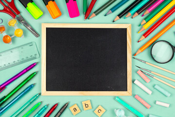 A Collection of Colorful Office Supplies Displayed on a Desk Next to a Blank Chalkboard