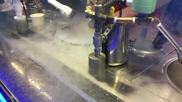 Man scoops ice cream into a bowl infused with nitrogen to make a trendy cold ice cream on site.