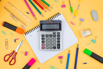Colorful calculator and stationery items on a vibrant yellow background for study or work
