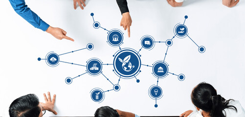 Top view of a collaborative business strategy session focusing on environmental solutions, featuring green icons and active discussions among diverse team members. Amity