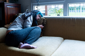Sad woman suffering from depression, lying on the sofa at home