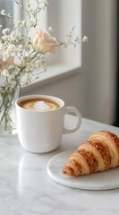 A white marble table with coffee, croissant, and baby’s breath flowers in a vase.
