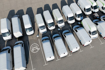 Rows of white electric delivery vans at charging stations for electric vehicles © scharfsinn86