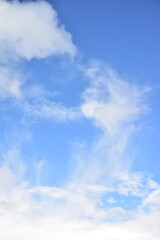 Unusual light clouds against the blue sky on a sunny summer day. Vertical view of the sky.