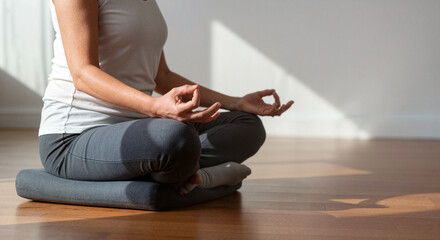 Woman in lotus position meditating on cushion. Mindfulness and wellbeing. Healthy lifestyle for website, blog, meditation practice. Copy space.