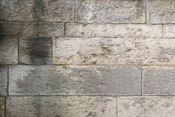 Weathered and discolored stone wall provides a textured background, showcasing the effects of time and elements