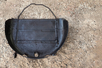 Old metal container resting on the ground among gravel, showcasing rust and wear from years of use in outdoor environments