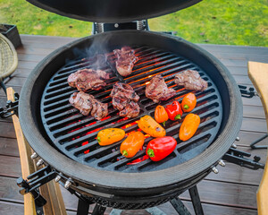 A kamado egg type barbeque grill standing on a living house terrace with beef sirloin steak, filet...