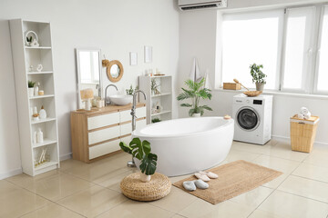 Interior of bathroom with bathtub, washing machine and wicker mat