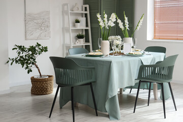 Interior of light room with served dining table and white Gladiolus flowers