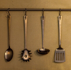 tableware on kitchen with ladles serving spoon and spatula for cooking hanging in the kitchen above...