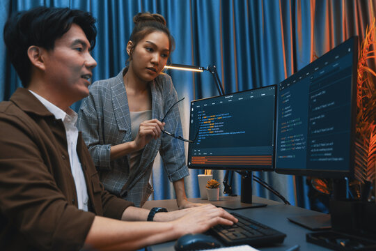 IT developers discussing with point to intelligent website development coder system running data online two screens information technology at neon light room at modern office. Infobahn.